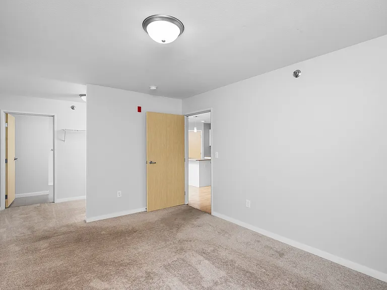 Bright and spacious room with plush carpeting, clean white walls, and modern light fixtures. Bright and spacious room with plush carpeting, clean white walls, and modern light fixtures.