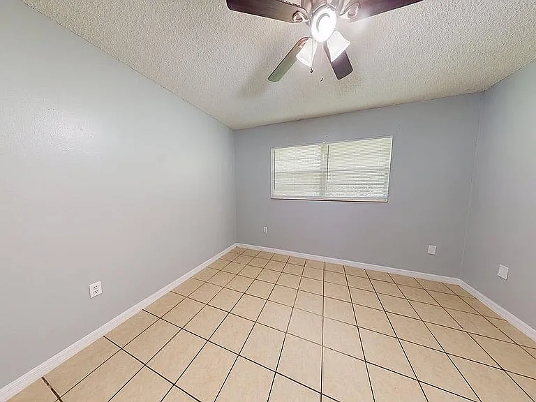 Bright, spacious room with modern ceiling fan and elegant tiled flooring, perfect for a cozy living space or home office.