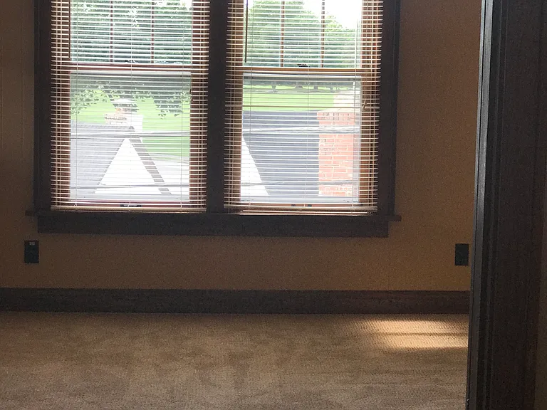 Carpeted sunroom, looks out onto nearby park, access to small balcony