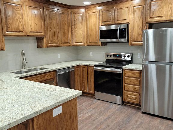 Kitchen with custom wood cabinetry, brand new stainless steel appliances, bar seating, vinyl plank flooring, flush mount LED lighting