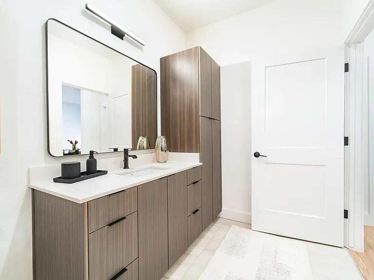 This bathroom showcases a sleek vanity with ample drawer and cabinet storage, along with a tall linen cabinet for added organization.