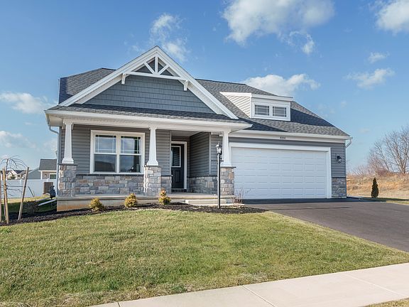 Gray ranch home with stone accents, covered front porch, and two-car garage in S A Homes community
