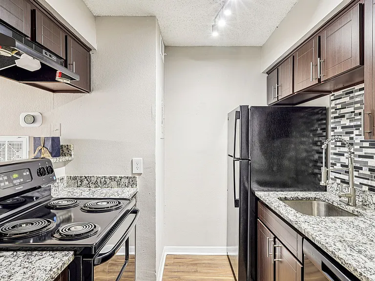 Updated kitchen with granite countertops, modern cabinetry, tile backsplash, and full-size appliances.