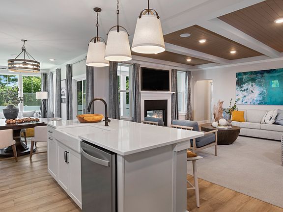Open kitchen, dining area and family room with 2-sided fireplace in a DRB Homes Fiji model home.
