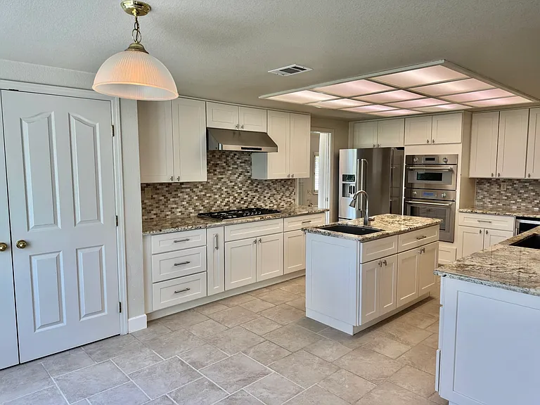 Remodeled kitchen featuring an island, dual sinks, and marble countertops