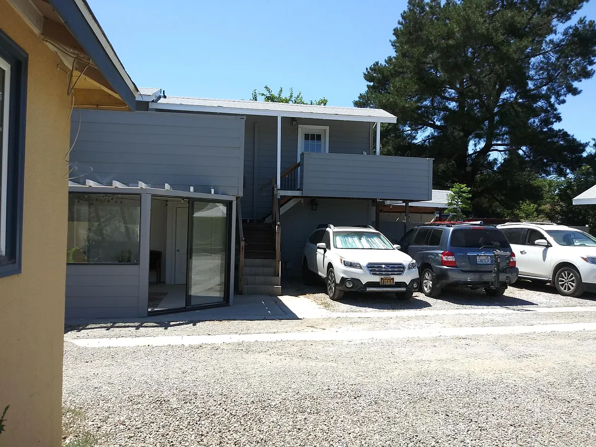 Parking and entry stairs for unit #3. The white Subaru is in the parking space allotted to unit #3. Wall on the left fronts unit #3's front deck (see floor plan). Door to the right is our office. - Elm St