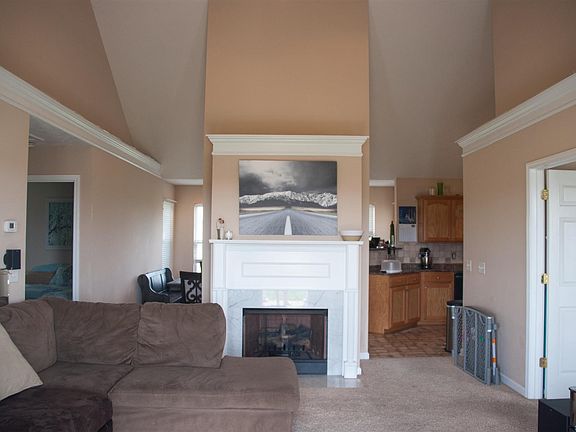 Living room w/vaulted ceiling, propane fireplace w/mantle, and ceiling fan.