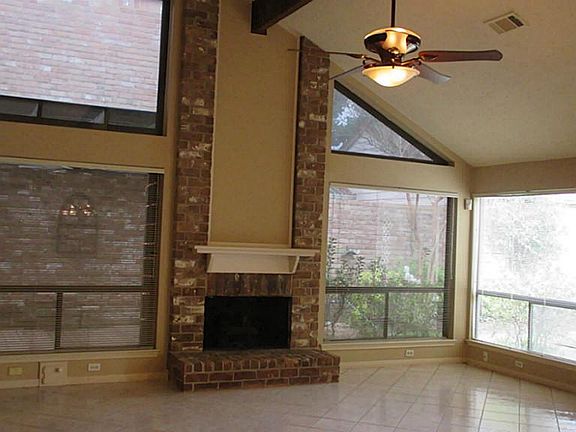 Living room boasts vaulted ceiling, gas log fireplace, tiled flooring and two tone paint.