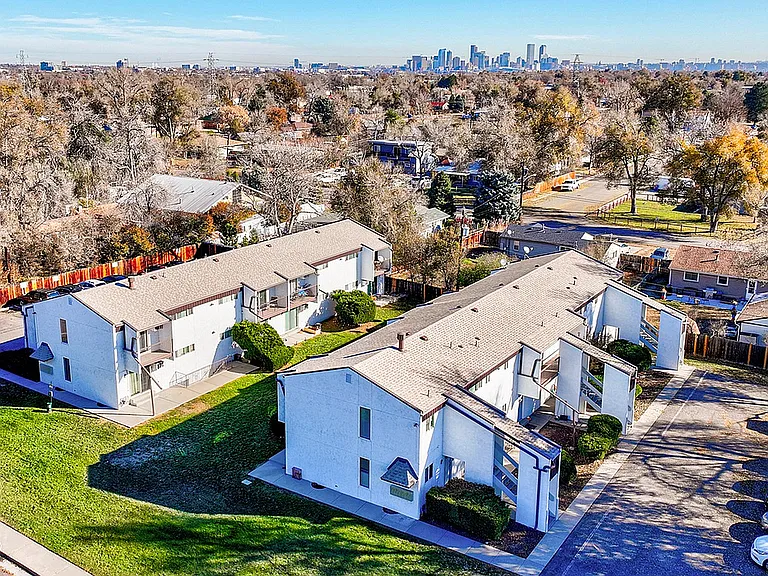Charming apartment complex with lush greenery, situated in a peaceful neighborhood, offering stunning city skyline views.