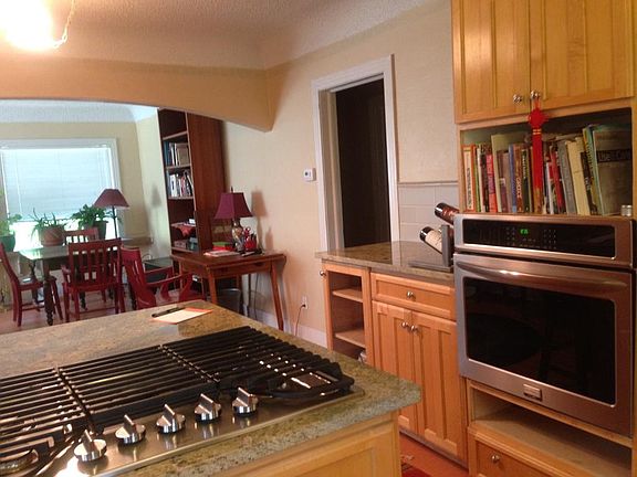 Open floor plan seen from kitchen peninsula into dining area beyond. Gas cooktop and wall oven in foreground.