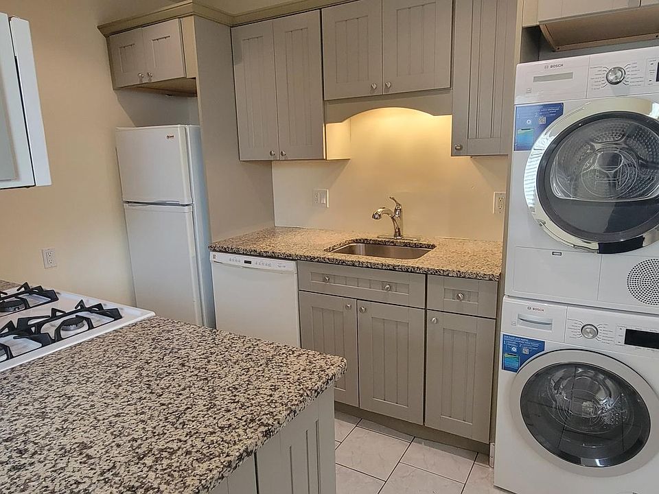 Kitchen with granite counters, gas stove, tile floor and Bosch washer and dryer.