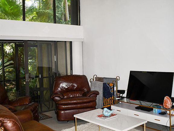 Living Room with floor to ceiling windows and front, screened in patio.