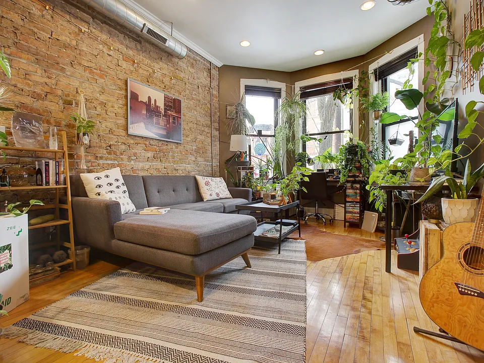Living room with beautiful bay windows, recessed light fixtures, 10 foot ceilings, exposed Chicago brick accent wall, and beautifully restored hardwood floors