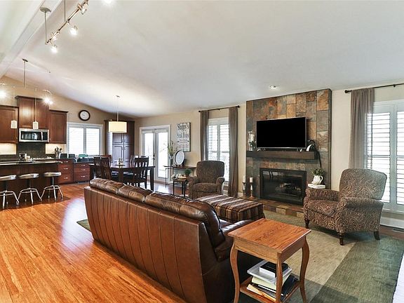 Great room has a high cathedral beamed ceiling, slate tile surround gas fireplace and hearth, great natural light from the newer insulated Pella windows, attractive lighting and fabulous Bamboo wood floor