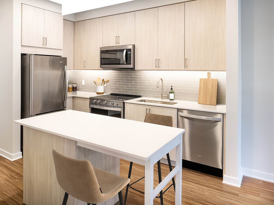 Upgrade Collection kitchen with oak cabinetry, stainless steel appliances, cream quartz countertops, and hard surface flooring