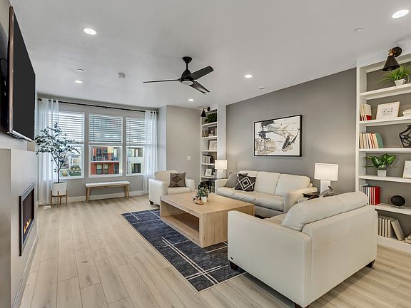 A modern living room featuring two white sofas, a wooden coffee table, and bookshelves beneath a wal