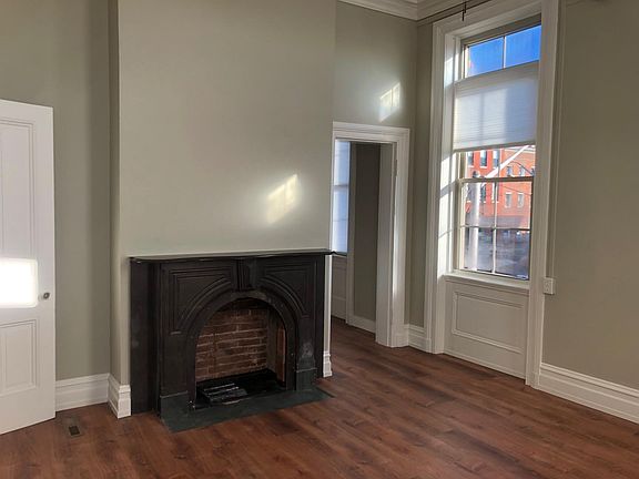 Decorative fireplace; bathroom door is to left, entrance to kitchen at right.
