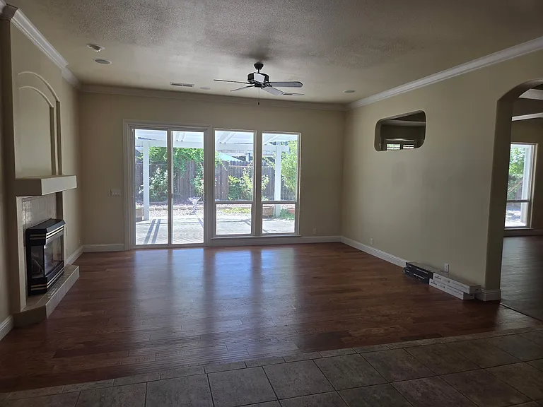 Family room that opens to kitchen, with gas fireplace, ceiling fan, sliding glass door that opens to the beautiful backyard