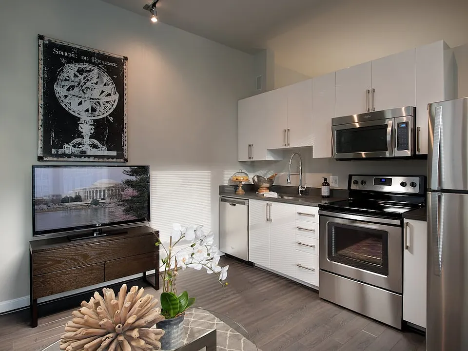 Open concept kitchen with white cabinetry, quartz countertops, stainless-steel appliances and hard surface flooring