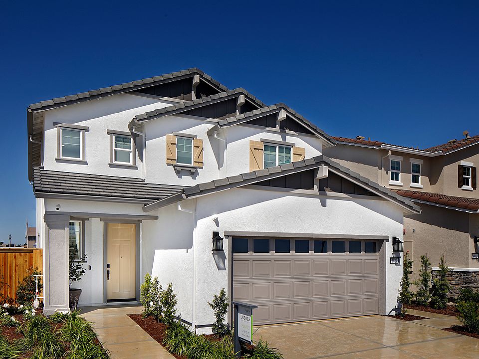 A two-story residential house with a garage, surrounded by a well-maintained lawn and landscaping, s