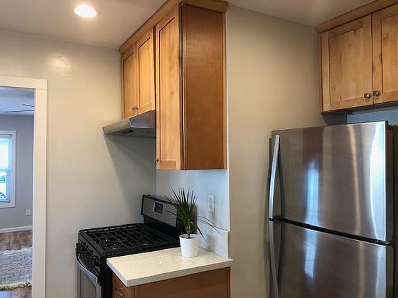Another view of the kitchen, with stainless steel appliances including gas stove and refrigerator.
