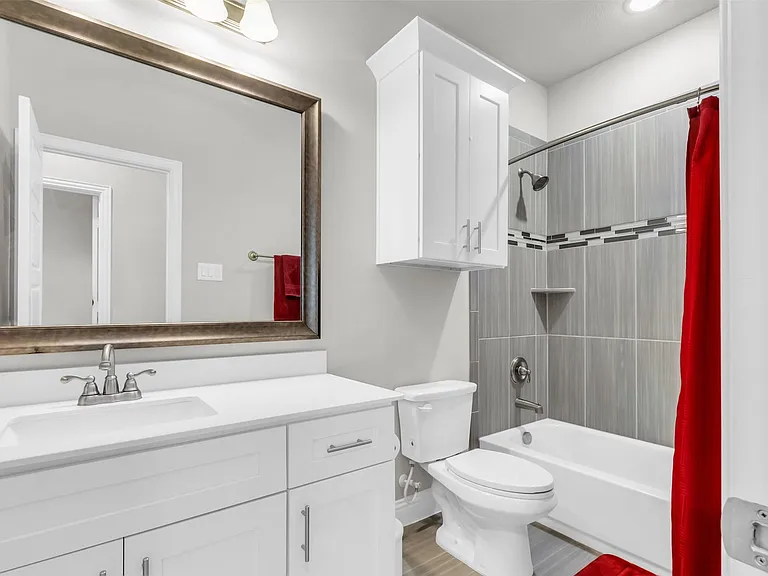 Bathroom featuring a single vanity with an undermount sink, a large framed mirror, and white cabinetry