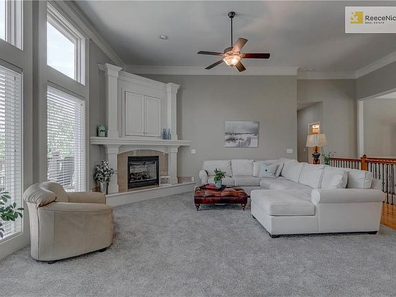 Great room with tall ceiling, corner fireplace, cabinet for entertainment center. View of deck and greenspace.