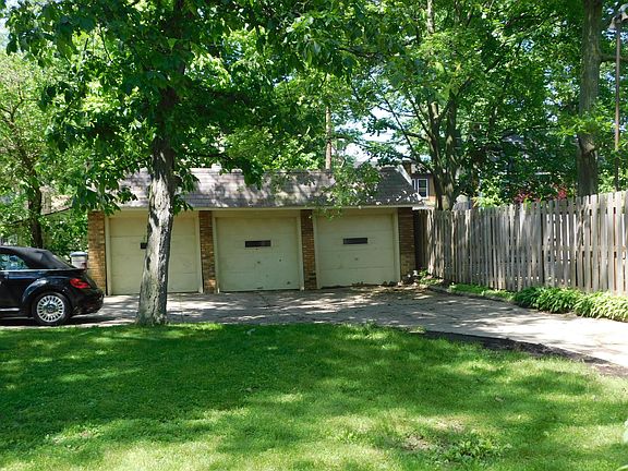 Fenced yard on right side with three garage spaces and extra parking.