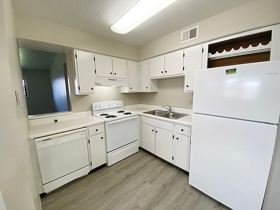 KITCHEN FROM DINING AREA; STOVE DISHWASHER, REFRIGERATOR WITH BUILT IN WINE RACK ABOVE