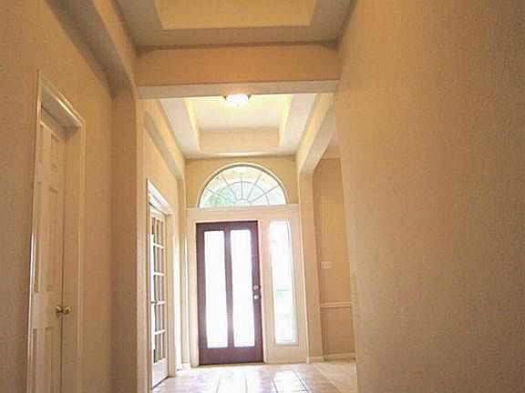 Beautiful tiled entry and hall with double-tray high ceiling and neutral paint.