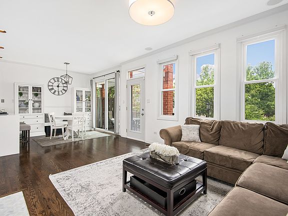 The open concept living/dining area has dark hardwood floors throughout and is flooded with afternoo