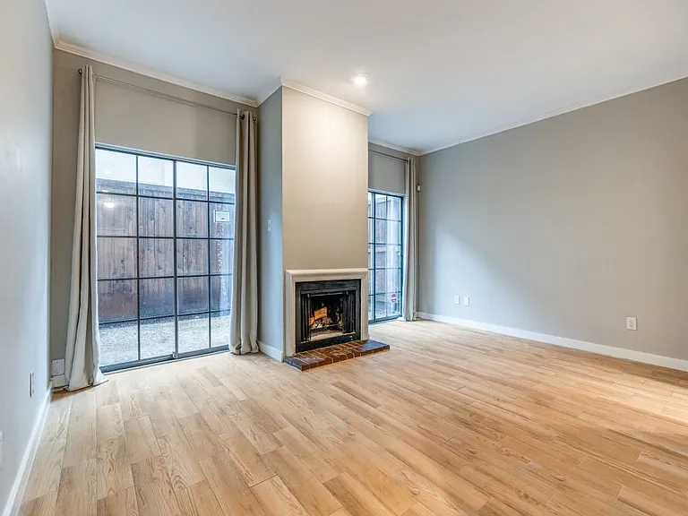 High ceilings & fireplace in this living room with access to the open patio outside.