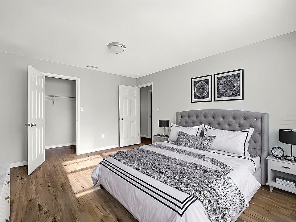 Elegant bedroom featuring a plush gray tufted headboard, modern decor, and abundant natural light highlighting the stylish wood floors.