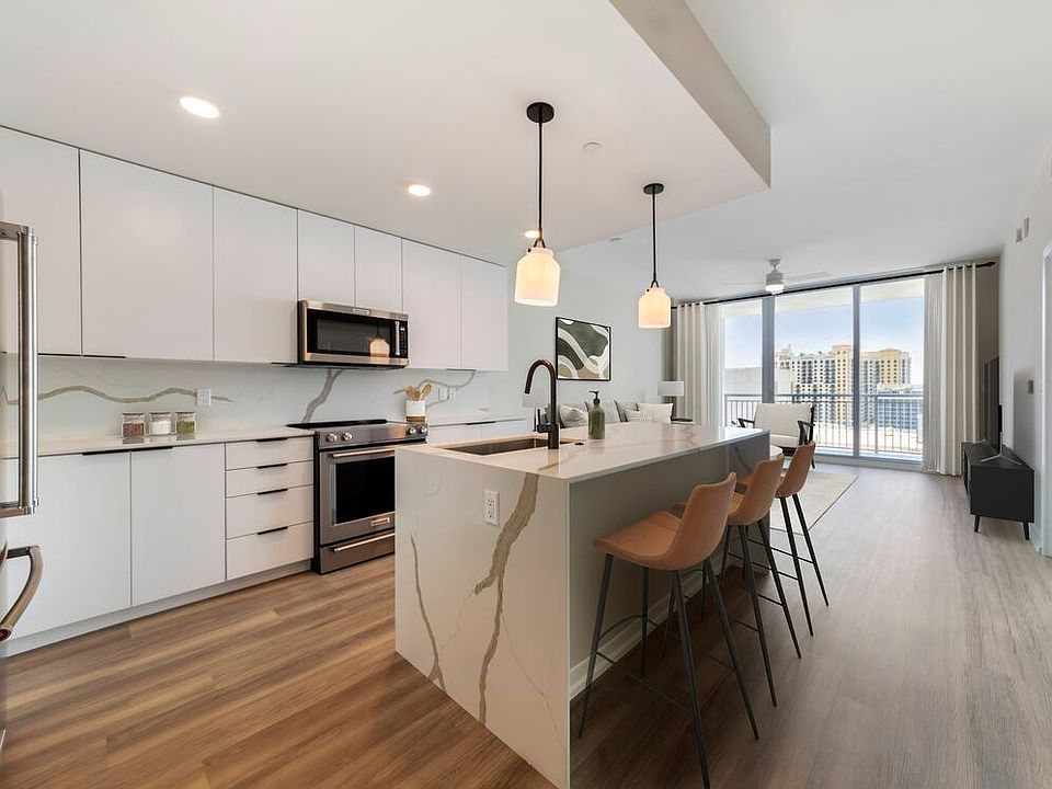 Tower Building - Renovated kitchen with stainless steel appliances, marbled white quartz countertops, light grey cabinetry, and hard surface flooring