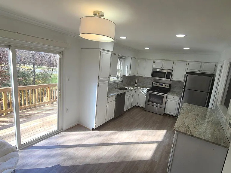 Kitchen: new granite countertop, stainless steel appliances. Window above kitchen sink faces wooded lot.