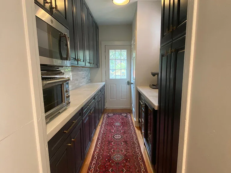 Butler pantry with wine refrigerator and refrigerator drawers. Space also contains coat closet and door to backyard.
