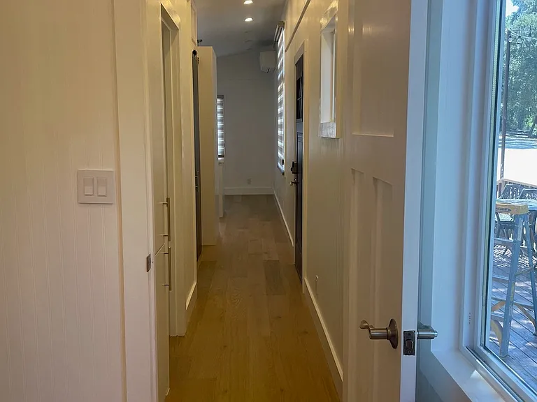 Looking down the hallway from the bedroom towards the bathroom, office/study, and kitchen/living area at the end.