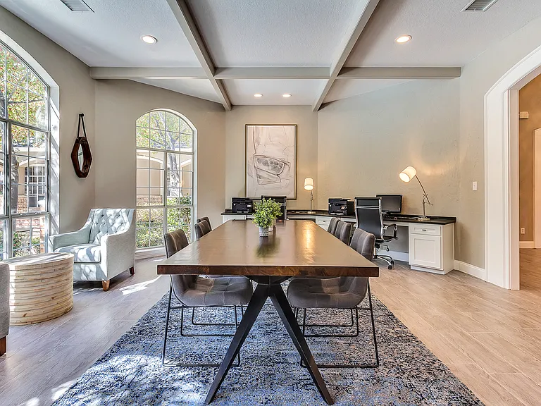 Business center boasting natural lighting and large windows with conference table, computers and printer