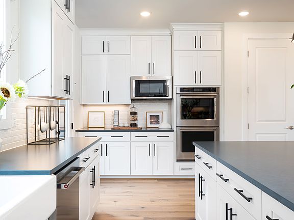 A modern, well-equipped kitchen with white cabinets, stainless steel appliances, and a sleek, minima