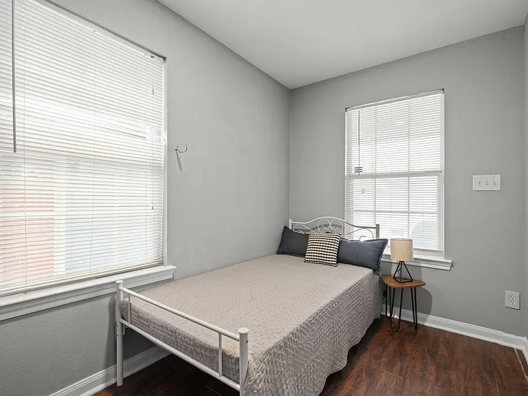 Twin sized bed & mattress in a cozy bedroom w/ writing desk & chair, closet rack.