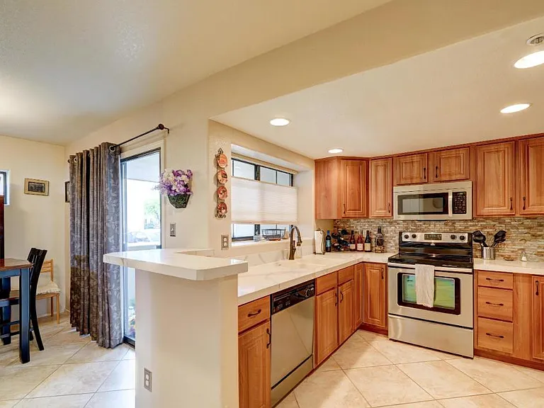 Kitchen has small eat-in bar adjacent to dining/living room with access to patio for open concept living.