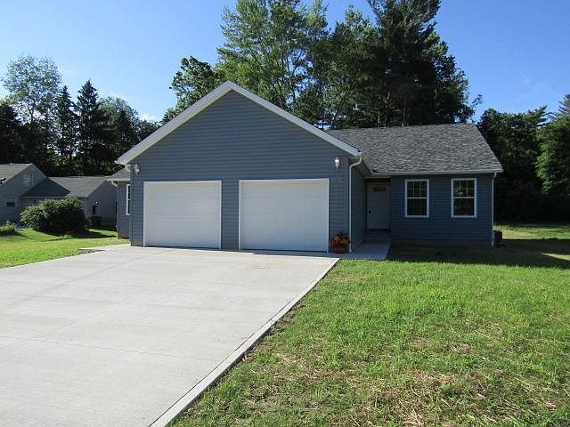 Blue-sided, white trimmed twin-plex has 1-car garage and cement driveway per unit.