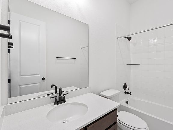 The secondary bath features tile flooring, brown cabinetry and light countertops and a shower tub co