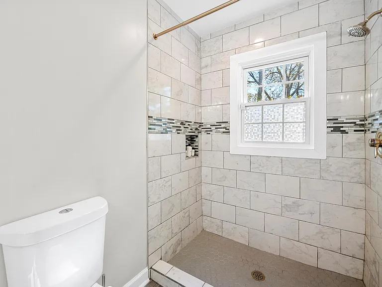 Nestled within the master bedroom is a private bathroom offering a stand-up shower with a charming window, and natural light.