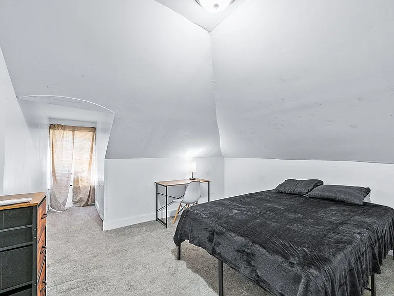 Upper-level bedroom with vaulted ceilings, a desk workspace, and a window nook for natural light and ventilation.