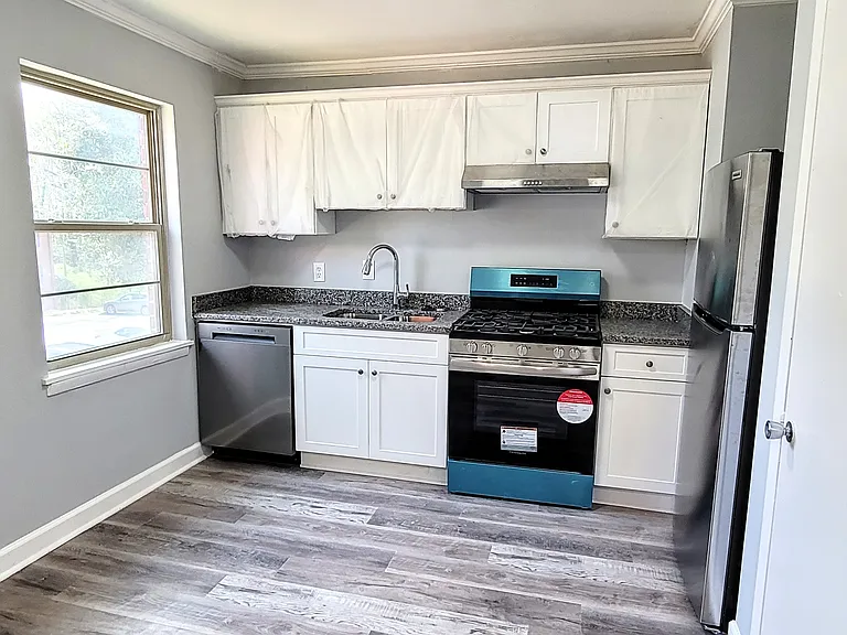 Chic, fully renovated white kitchen featuring brand-new stainless steel appliances