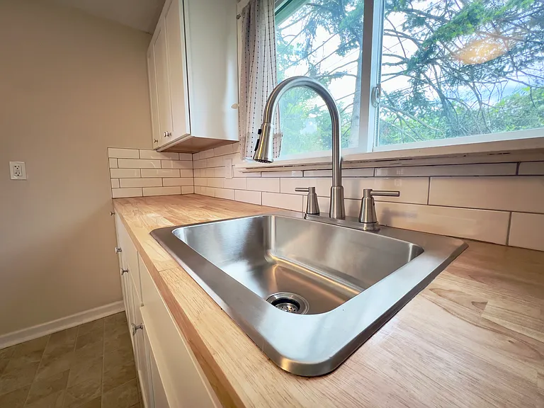 Brand new sink, faucet, butcher block countertop, subway tile backsplash, and cabinets