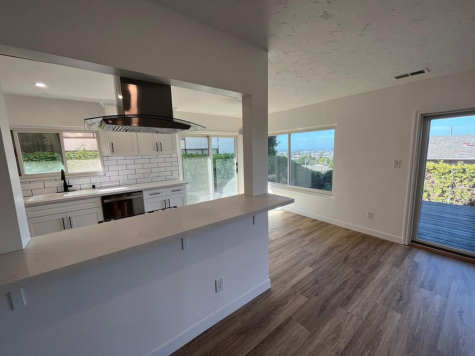 Living room looking through bar window to kitchen and outdoor deck/patio