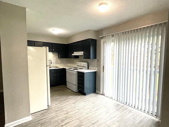 Newly updated kitchen counters, cabinets, all hardware and backsplash, with an area for a dining table that overlooks the lush greenway from the deck