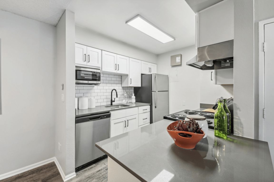 Upgraded kitchen with quartz countertops, stainless steel appliances, and tile backsplash